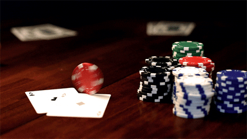 Poker chips stacked beside two aces on a card table
